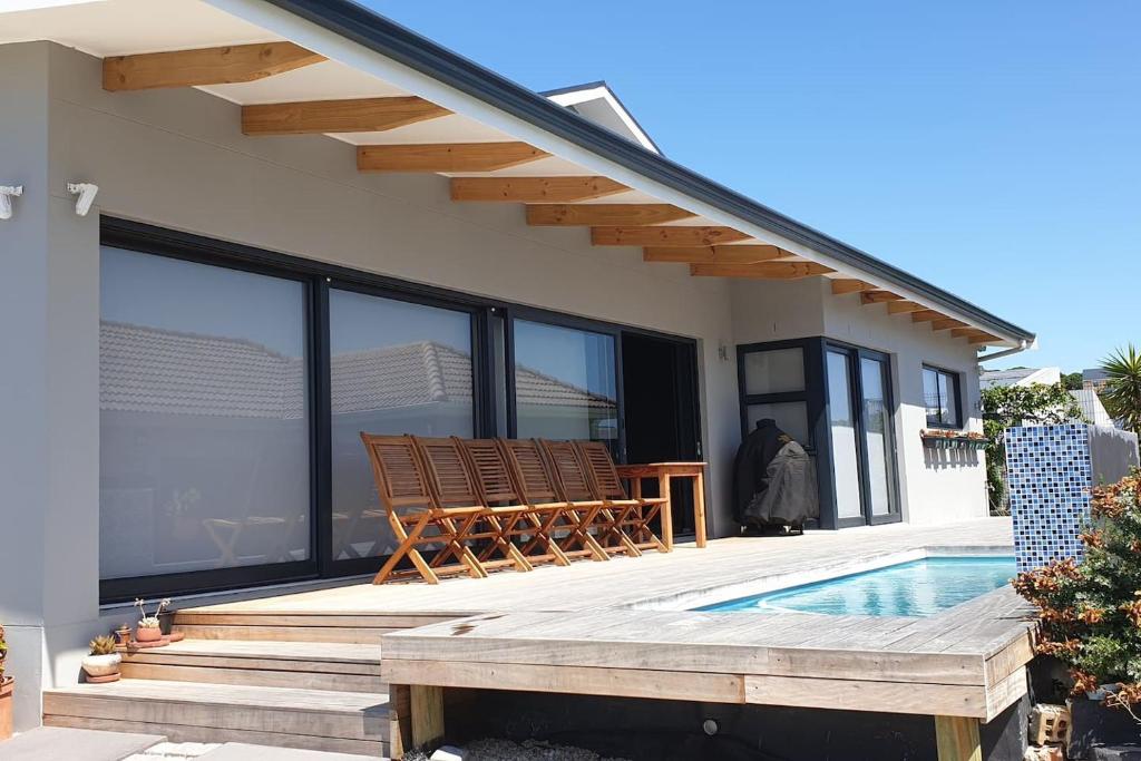 a house with a swimming pool and a deck with chairs at Serrulata House in Hermanus