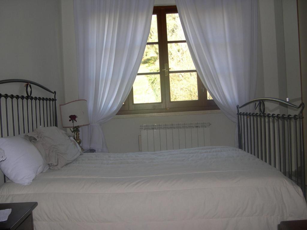 1 dormitorio con 1 cama con sábanas blancas y ventana en Il Boscaccio, en Camaiore