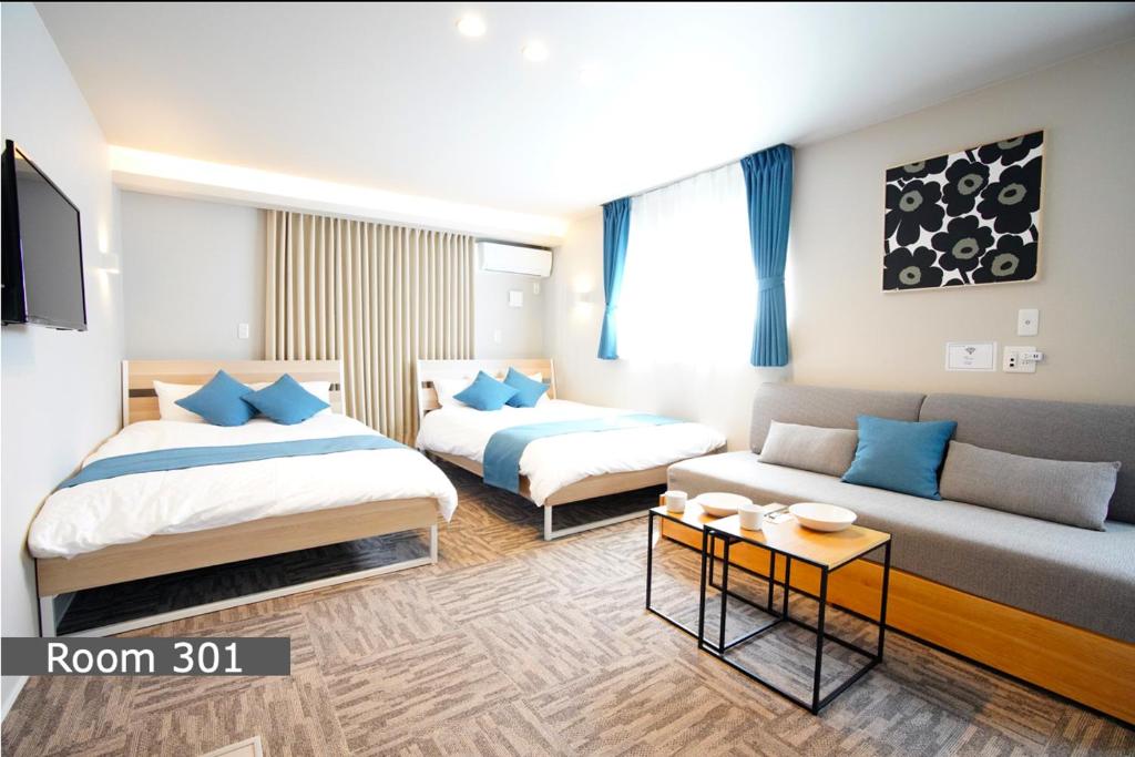 a hotel room with two beds and a couch at Koti Sopo Universal Bay 1 by Liaison in Osaka