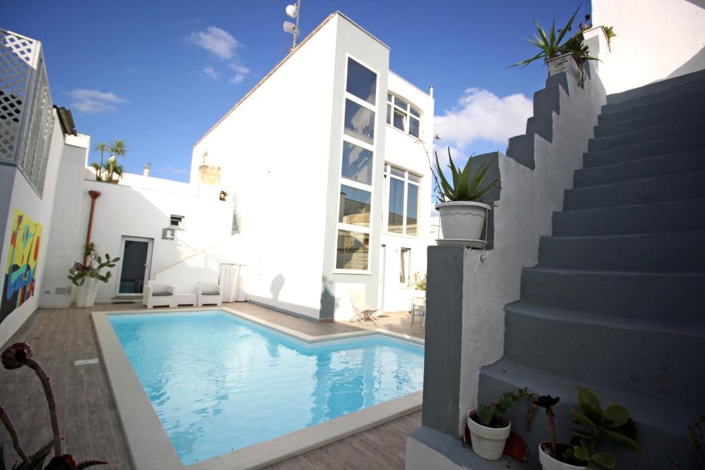 ein Pool neben einem weißen Haus mit einer Treppe in der Unterkunft Salentuosi Camere in Racale