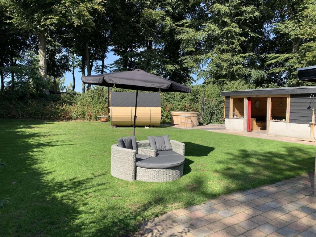 uma mesa e duas cadeiras debaixo de um guarda-sol num quintal em Holiday home with covered porch and sauna em Voorthuizen