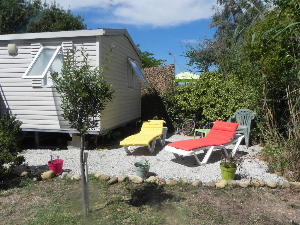 une arrière-cour avec deux chaises et une caravane dans l'établissement Mobil Home dans camping Lattes, à Lattes