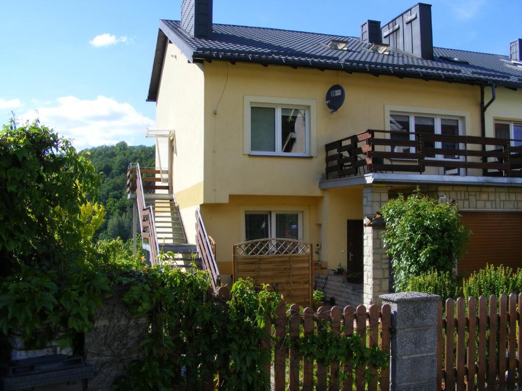 a yellow house with a fence in front of it at Pokoje gościnne Norbu in Kudowa-Zdrój