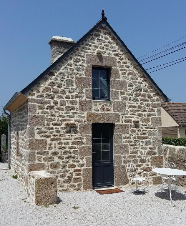 - un bâtiment en pierre avec une table et des chaises devant dans l'établissement La Boulangerie de Gitesocotentin, charmant cocon pour déconnecter, à Montfarville