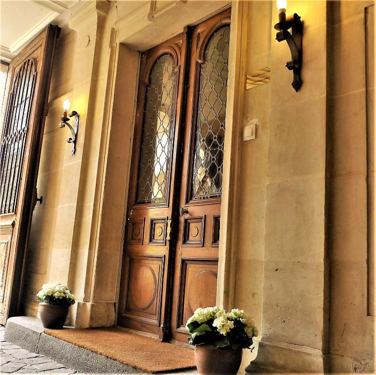 a large wooden door with two potted plants in front at Les chambres de l'Abbaye in Caen
