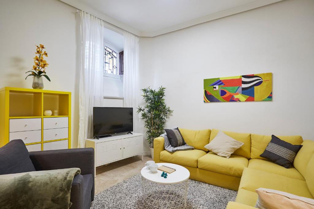 a living room with a yellow couch and a tv at LEEWAYS APARTMENT in ORIENTE in Madrid