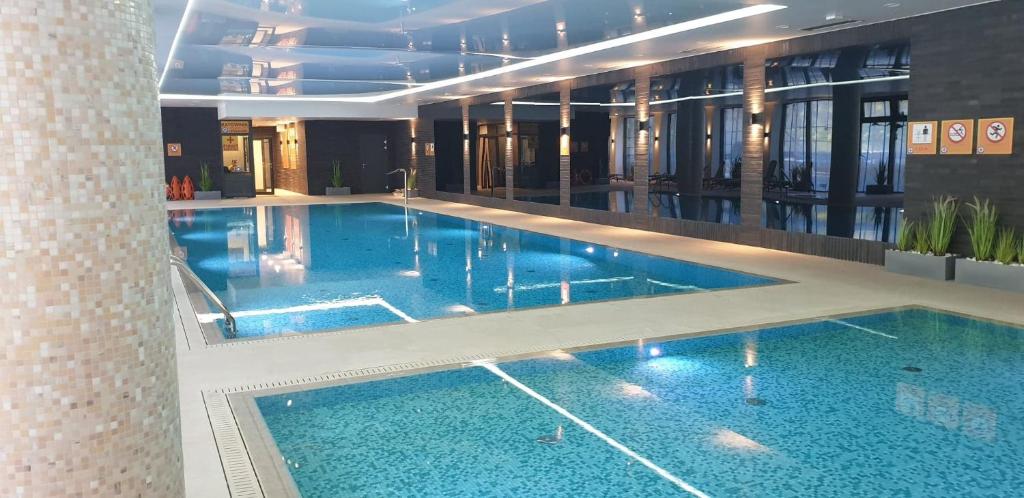 a large swimming pool in a building with blue water at Bodnar Apartamenty Nadmorskie Tarasy Port in Kołobrzeg