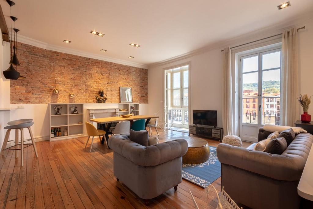 a living room with furniture and a brick wall at Confort y Diseño con Vistas al Casco Viejo in Bilbao