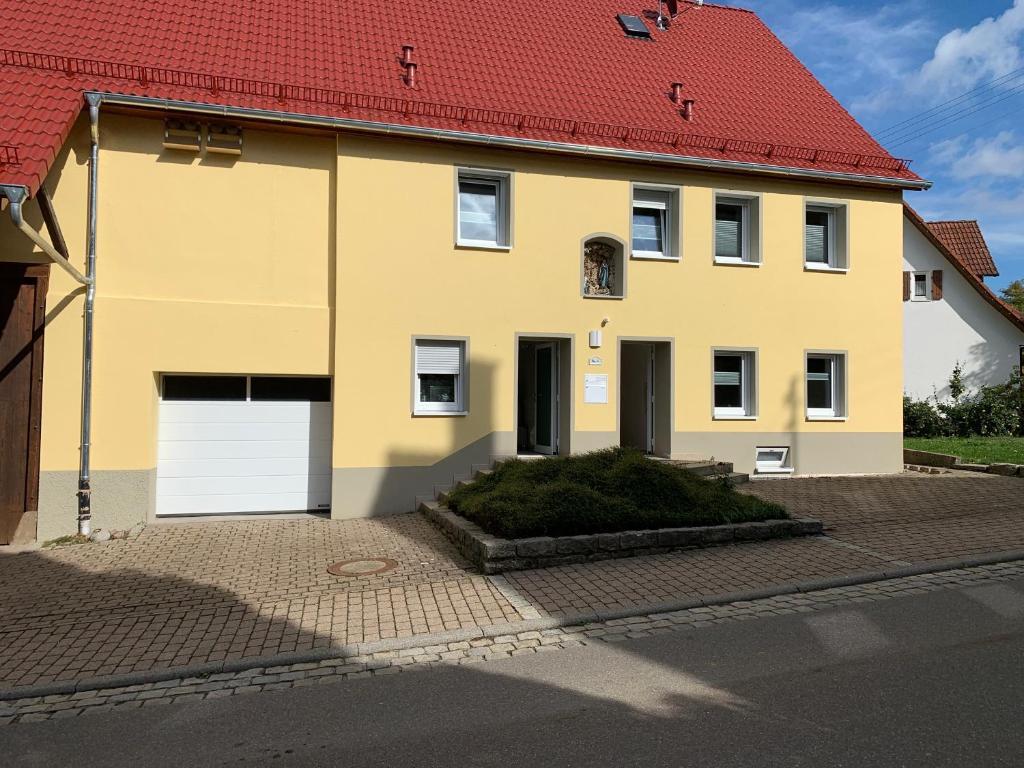 a yellow house with a red roof at Apartments beim Backhäusle in Starzach