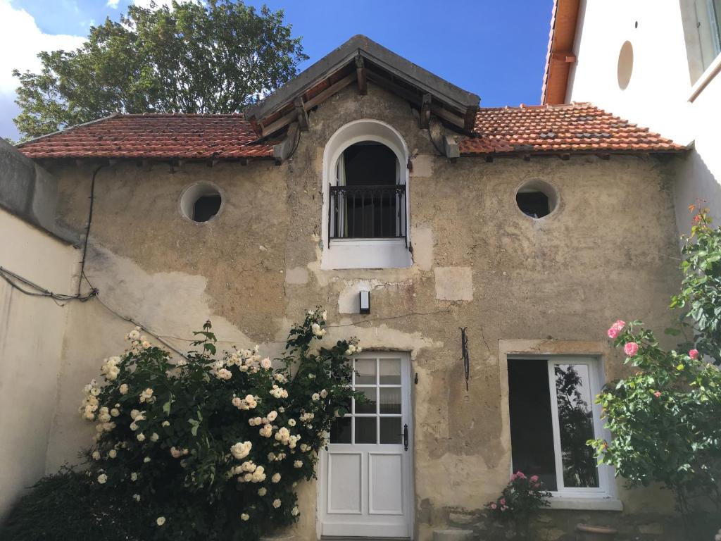 a stone house with a white door and flowers at Ferme de Pontaly in Bailly