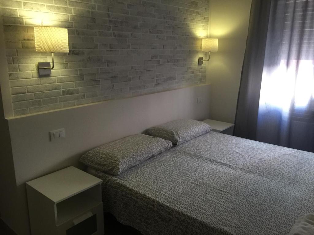 a bedroom with a bed and a brick wall at Bologna Centrale Stanze in Bologna