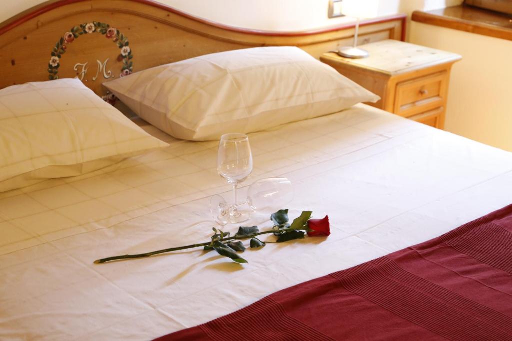 Una cama con dos copas de vino y rosas. en Luzzo 15, en Feltre
