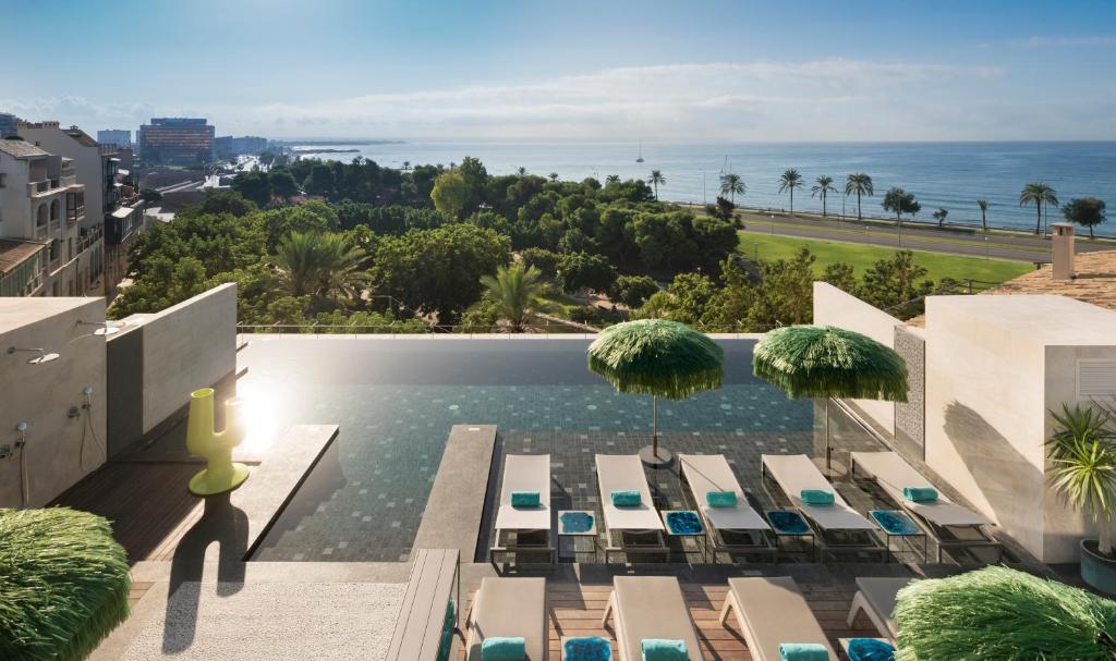 a pool with chairs and umbrellas and the ocean at El Llorenc Parc de la Mar - Adults Only (+16) in Palma de Mallorca