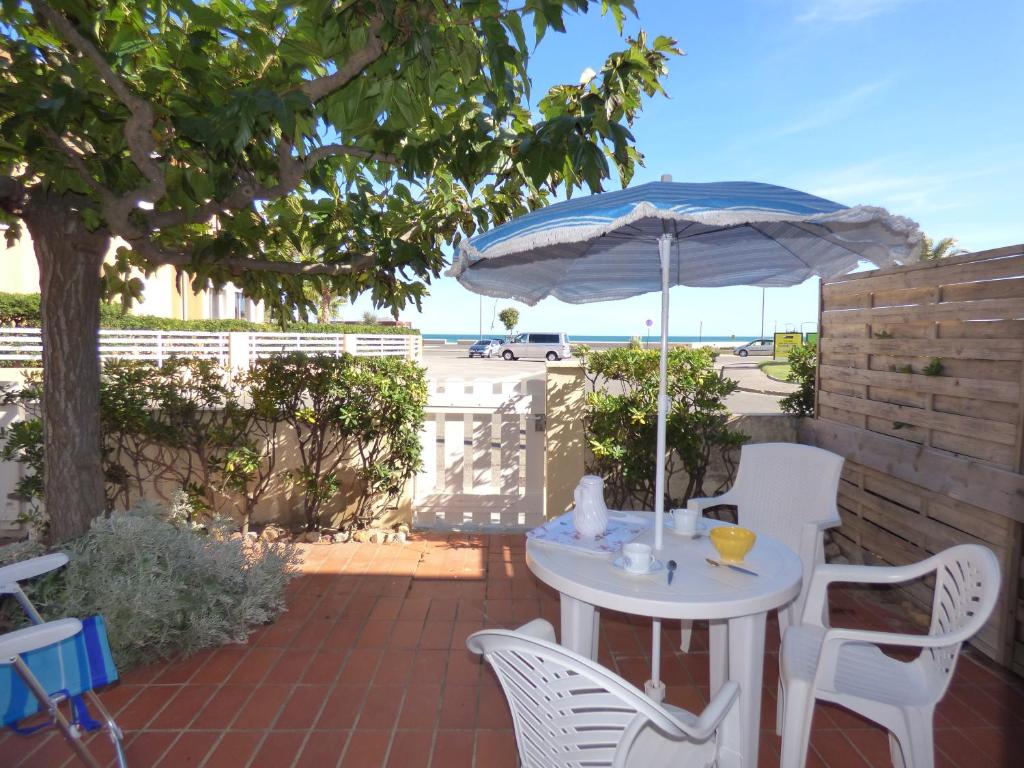 une table et des chaises avec un parasol sur une terrasse dans l'établissement Appartement T2 RDC, 2 couchages, Front de Mer Narbonne Plage, à Narbonne-Plage