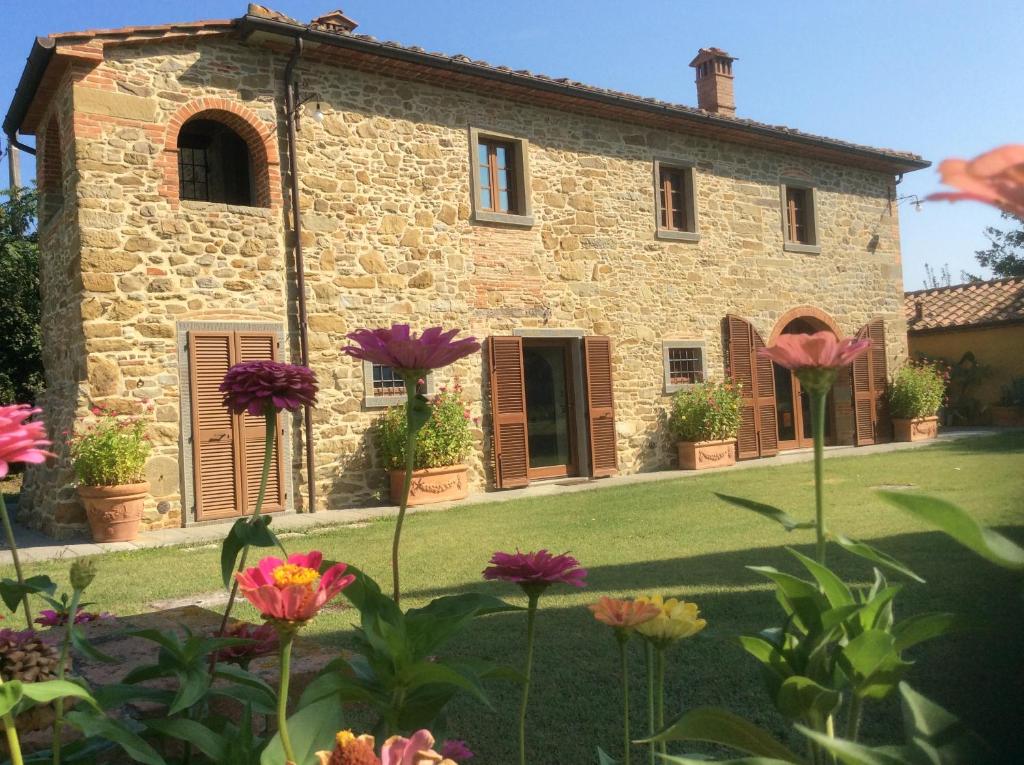 an old stone house with flowers in the foreground at VILLA Podere IL GIARDINO in Castiglion Fiorentino