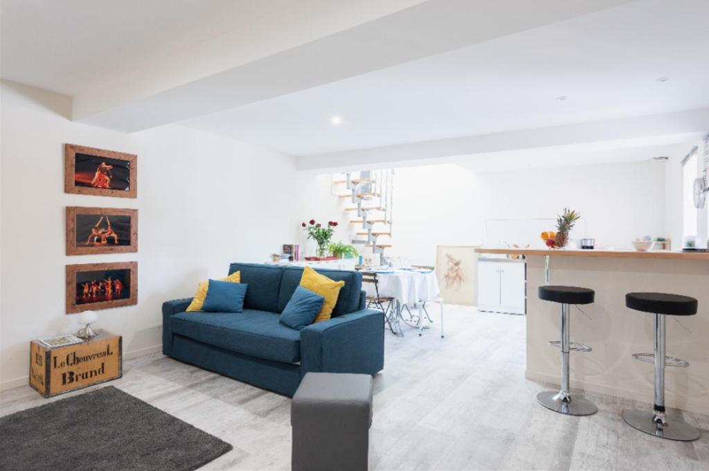 a living room with a blue couch and a kitchen at Grand duplex au calme en centre-ville in Villefranche-sur-Saône