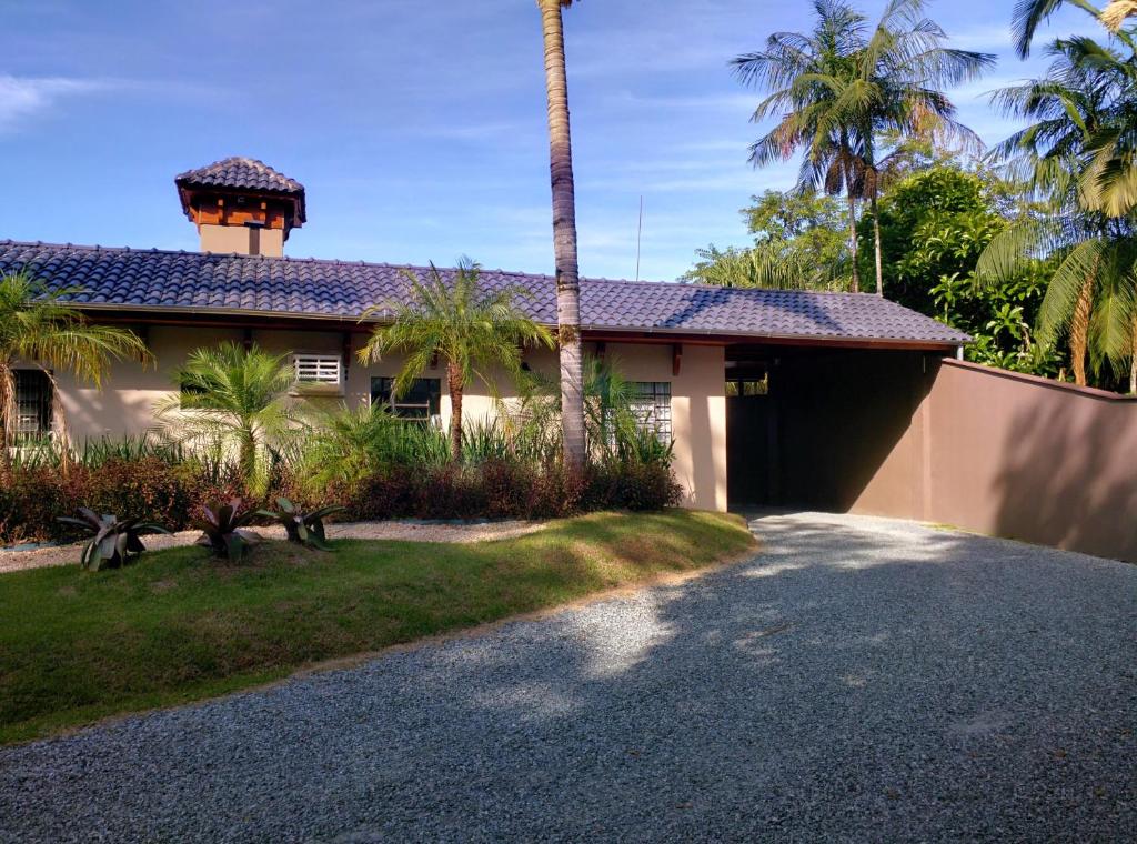 ein Haus mit einer Palme und einer Auffahrt in der Unterkunft Motel Cisne Blumenau (Adult Only) in Blumenau