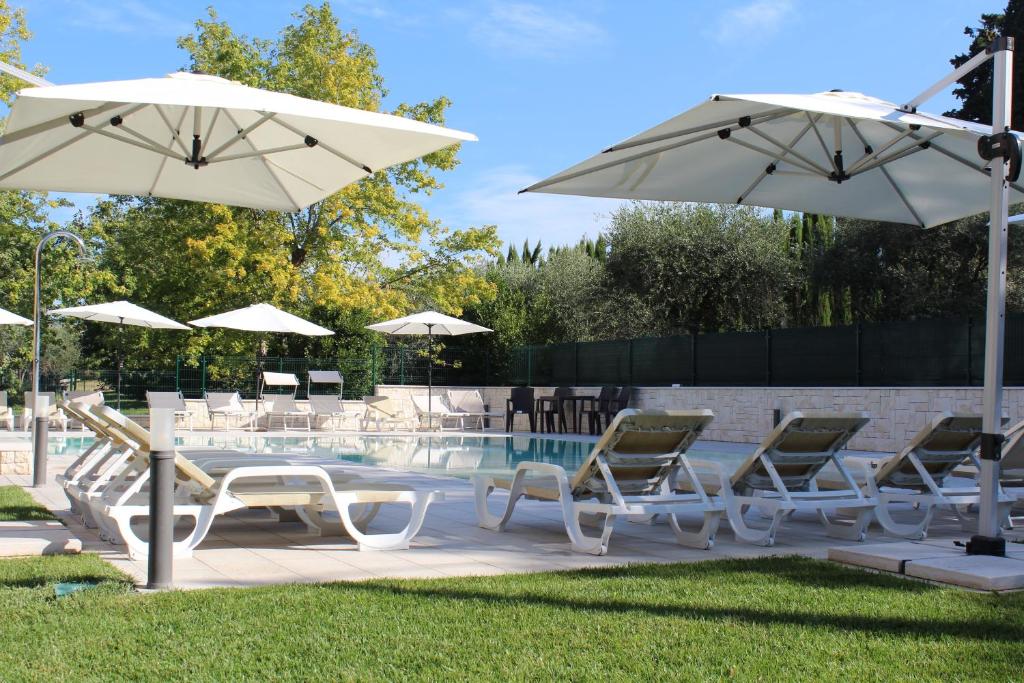 een groep stoelen en parasols naast een zwembad bij Residenza Sante in Lazise