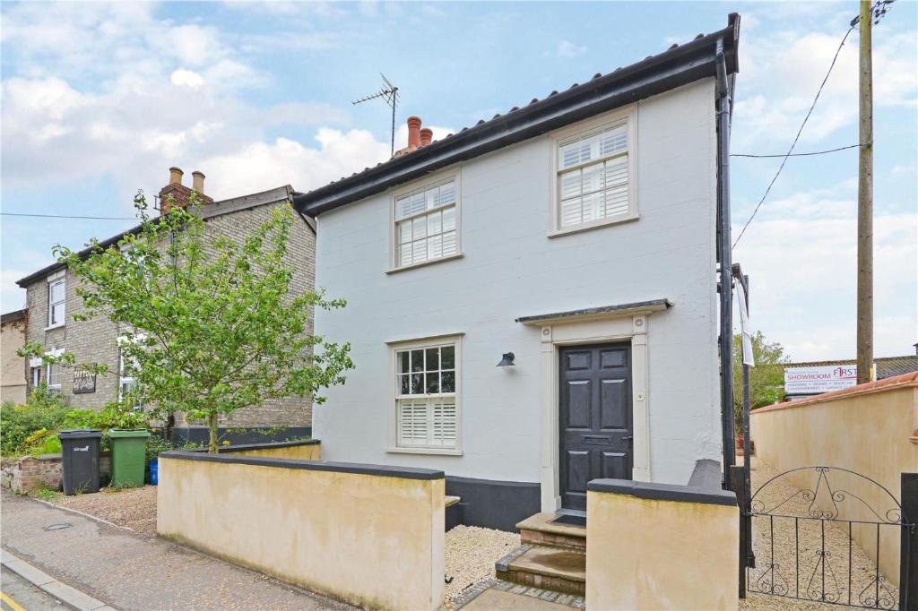 a white house with a black door on a street at Best located and beautifully renovated cottage in Diss