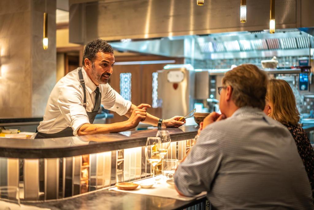 a chef preparing food in a restaurant kitchen at El Llorenc Parc de la Mar - Adults Only (+16) in Palma de Mallorca