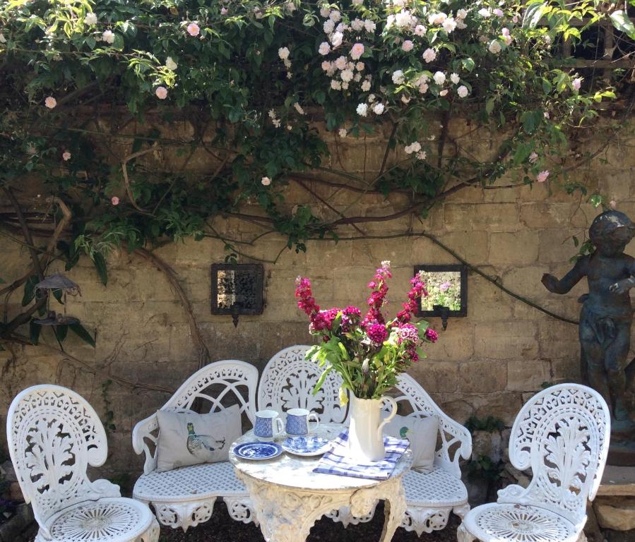 a table with chairs and a vase of flowers on it at Campden Mews in Chipping Campden