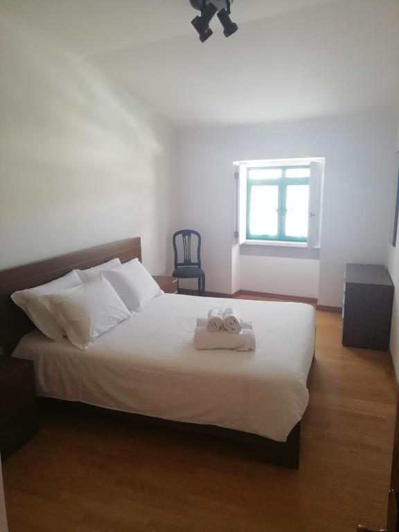 a bedroom with a white bed with two towels on it at Casa da Praça in Torre de Moncorvo