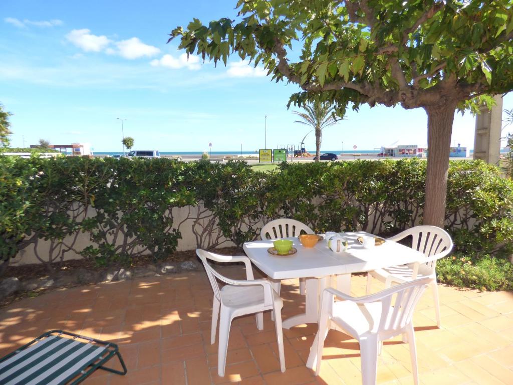 - une table et des chaises blanches avec vue sur la plage dans l'établissement Appartement T3, RDC, 4 couchages, Front de Mer Narbonne Plage, à Narbonne-Plage