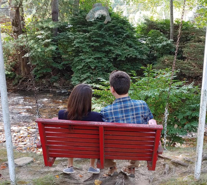 a man and a woman sitting on a red bench at Rolling Brook Inn in Maggie Valley