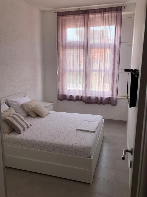 sypialnia z łóżkiem i oknem z różowymi zasłonami w obiekcie Visiani apartment w Szybeniku
