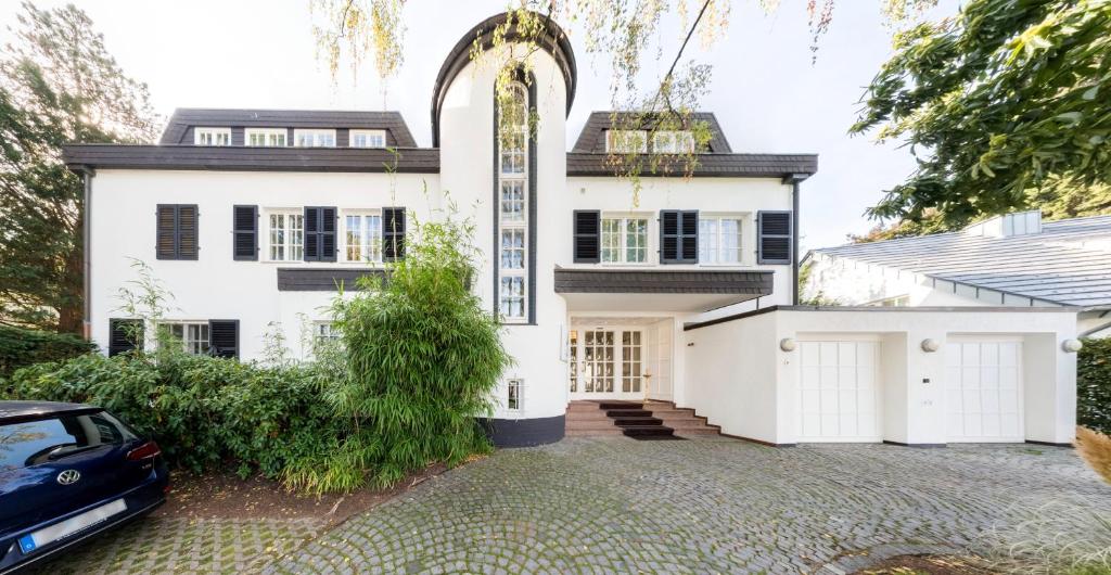 ein weißes Haus mit einem davor geparkt in der Unterkunft Hotel Villa im Park in Düsseldorf