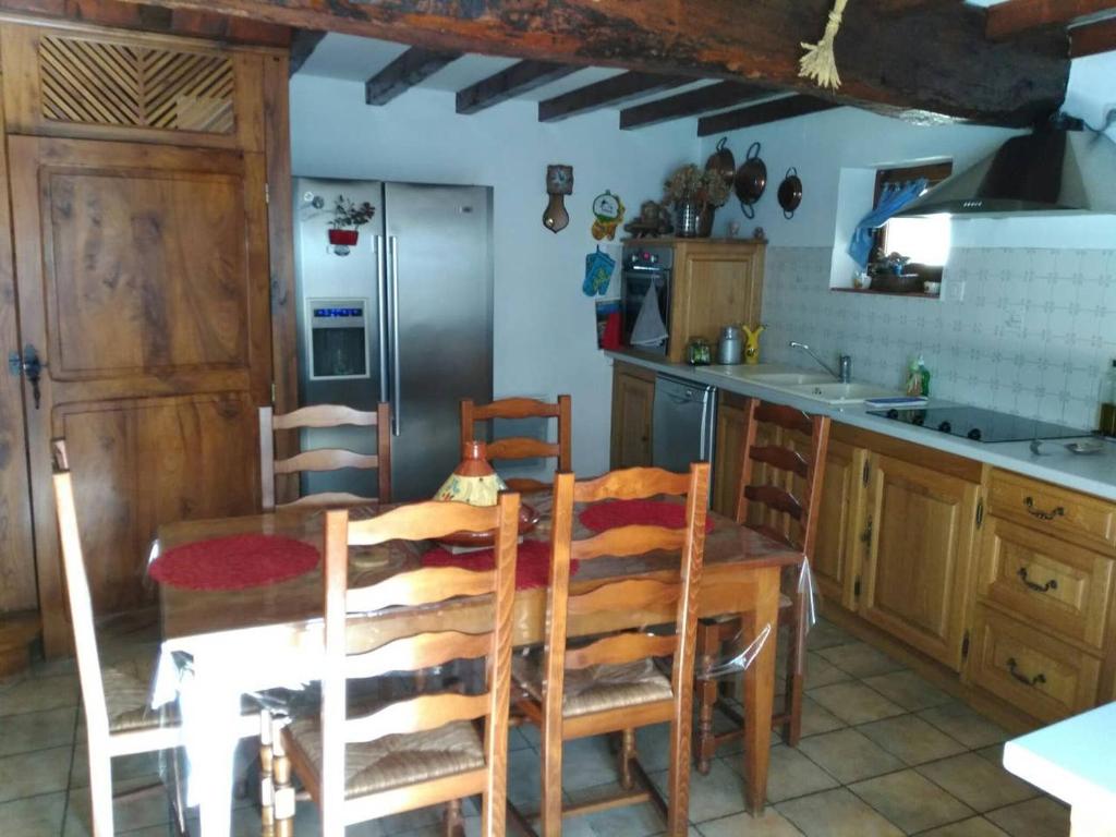 a kitchen with a wooden table and chairs and a kitchen with a refrigerator at CHAMBRE A LA CAMPAGNE - CHARENTE in La Rochette