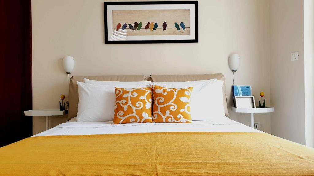a bedroom with a bed with orange and white pillows at Nerissa Holiday Apartment Milazzo in Milazzo