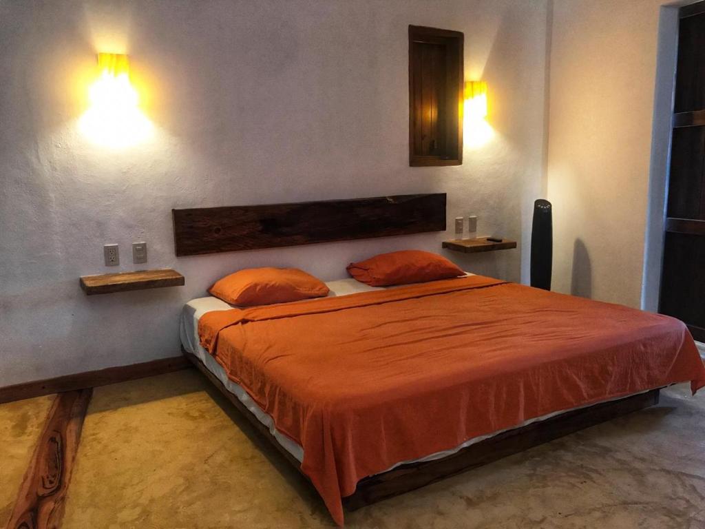 a bedroom with a bed with orange sheets and two pillows at Cuarto de Tim in Mazunte