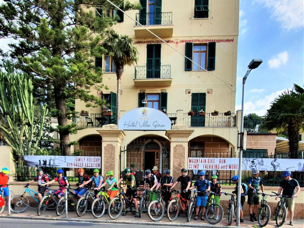 un gruppo di persone in bicicletta di fronte a un edificio di Villa Gina a Finale Ligure