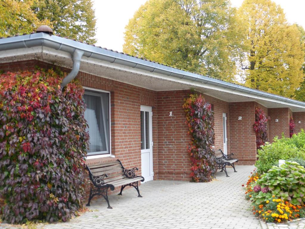 a brick building with a bench and a flower wall at Hotel Am Schlosspark in Mallin