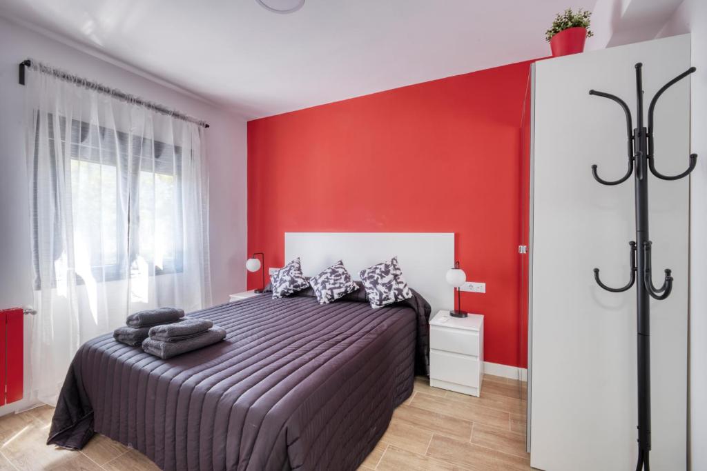 ein Schlafzimmer mit einem Bett mit einer roten Wand in der Unterkunft Ever House - ALCALA DIVA 1 ROOFTOP in Madrid