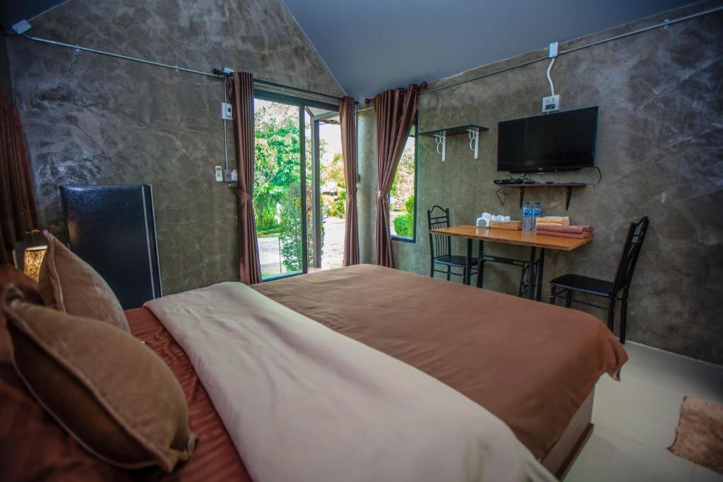 1 dormitorio con cama, mesa y TV en BR2 House Resort, en Phayao