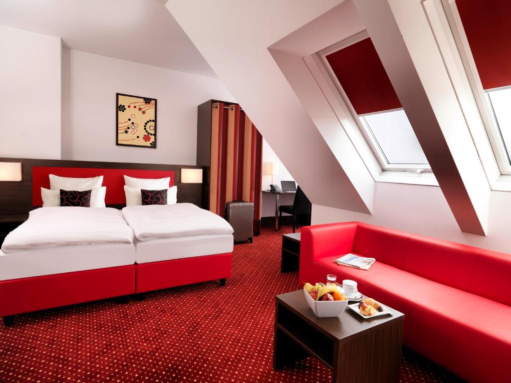 a hotel room with a bed and a red couch at Best Western Plus Amedia Wien in Vienna