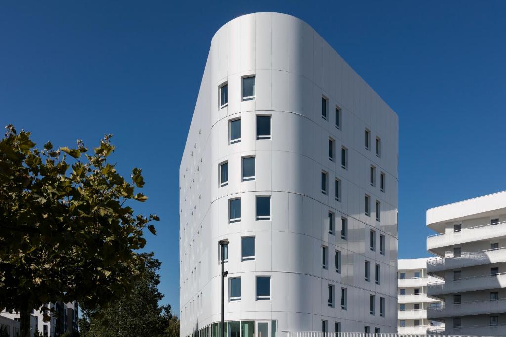 a white building with a blue sky in the background at Citadines Confluent Nantes in Nantes