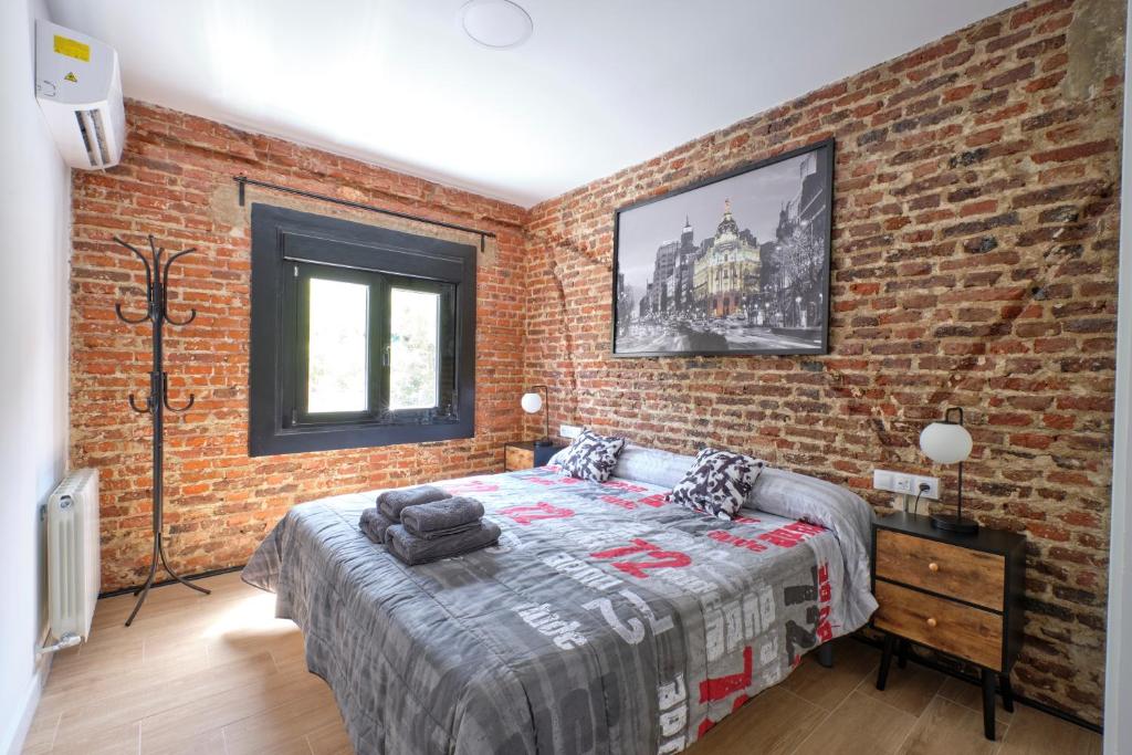 Un dormitorio con una pared de ladrillo y una cama. en Ever House - ALCALA DIVA 2 ROOFTOP, en Madrid