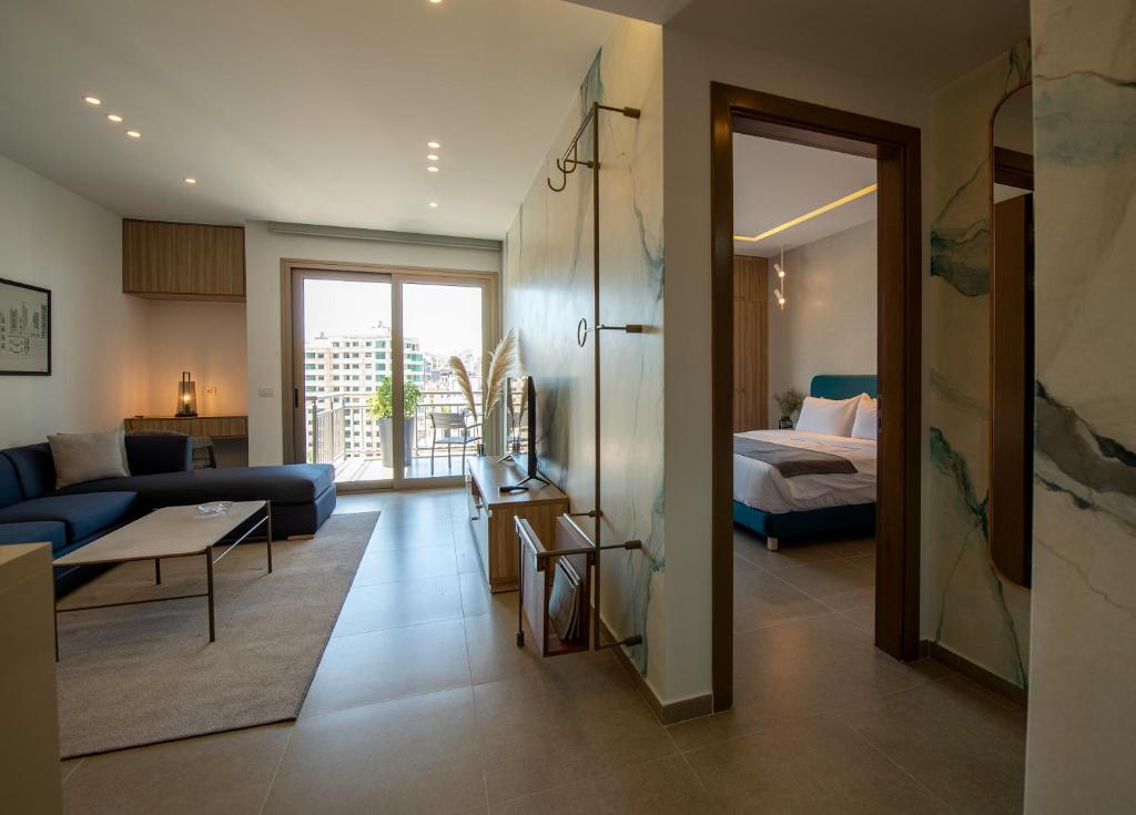ein Wohnzimmer mit einem blauen Sofa und einem Bett in der Unterkunft ZUR Studios and Suites in Beirut