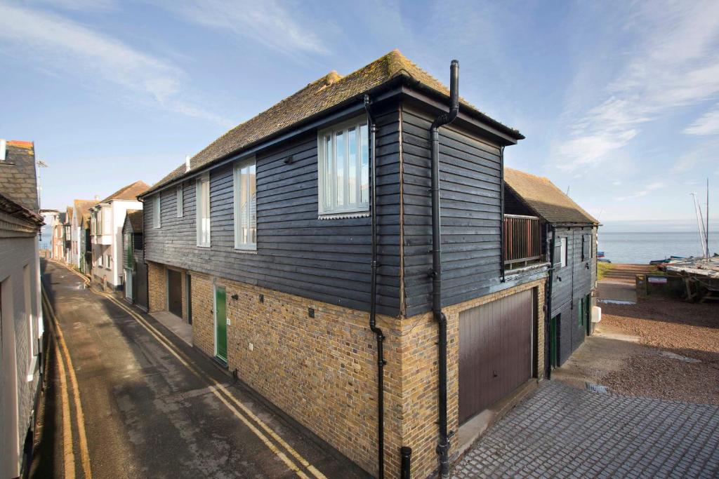 a black house on a street with the ocean in the background at Boat House in Whitstable