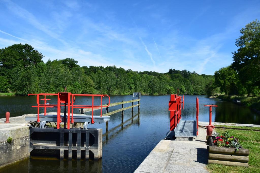 a dock with red structures on the water at Maison éclusière Le Port, Les Refuges du Halage in Sacé