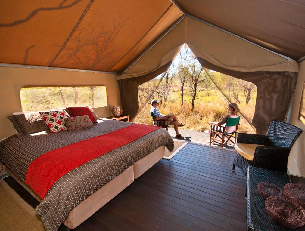um quarto com uma cama e pessoas sentadas numa tenda em Bungle Bungle Wilderness Lodge em Turkey Creek