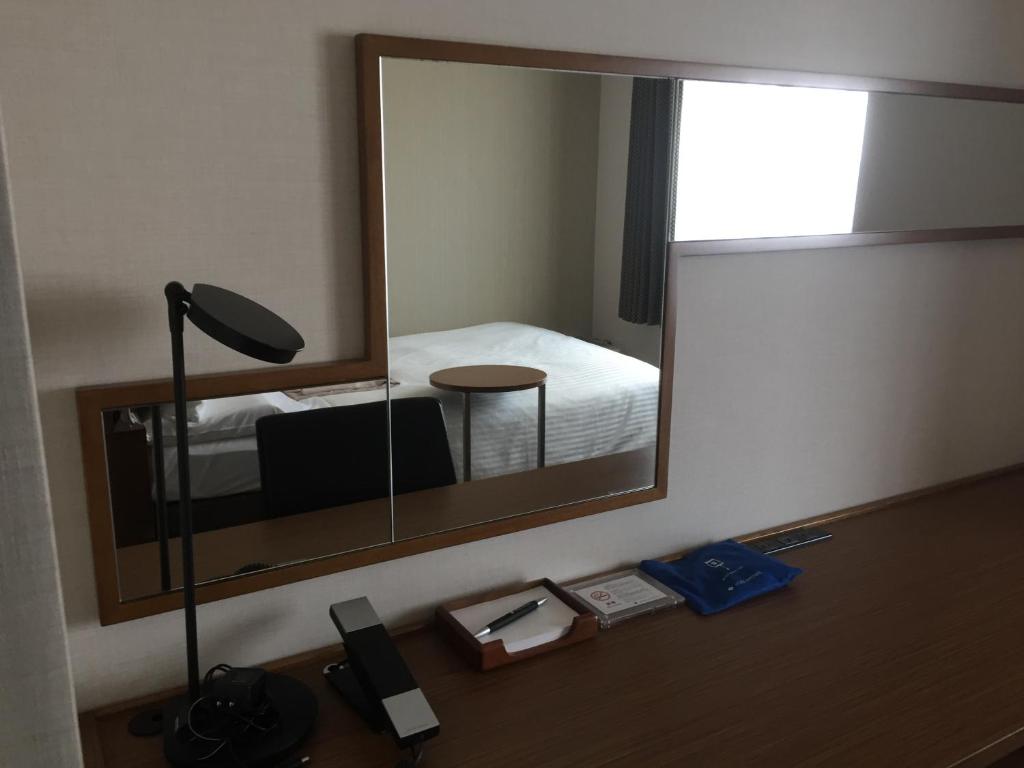a mirror in a room with a bed and a lamp at HOTEL MYSTAYS Kamata in Tokyo