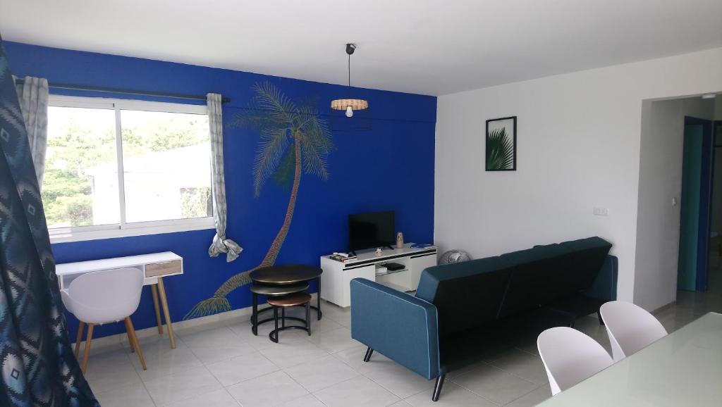 sala de estar con paredes azules, mesa y sillas en La Kay'Loulou avec spa et piscine, en Saint-Pierre