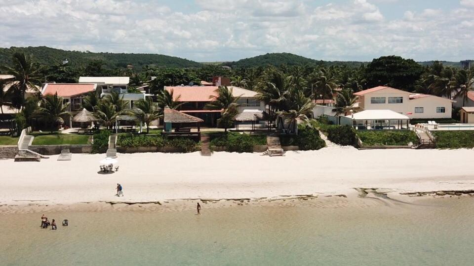 a group of people standing on a beach near the water at Linda casa à beira mar in Barra de São Miguel