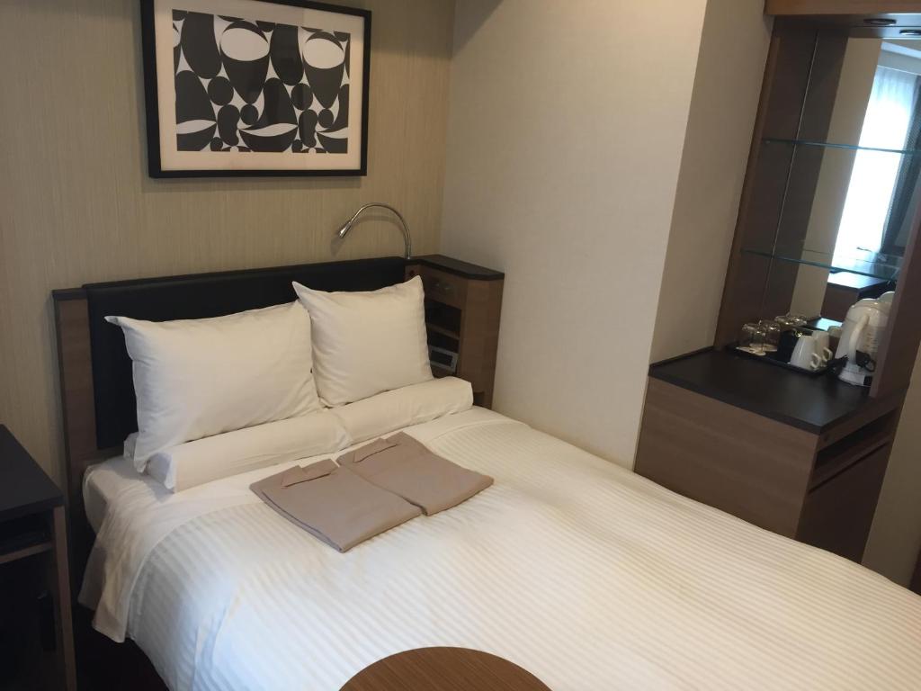 a bedroom with a white bed with a towel on it at HOTEL MYSTAYS Kamata in Tokyo