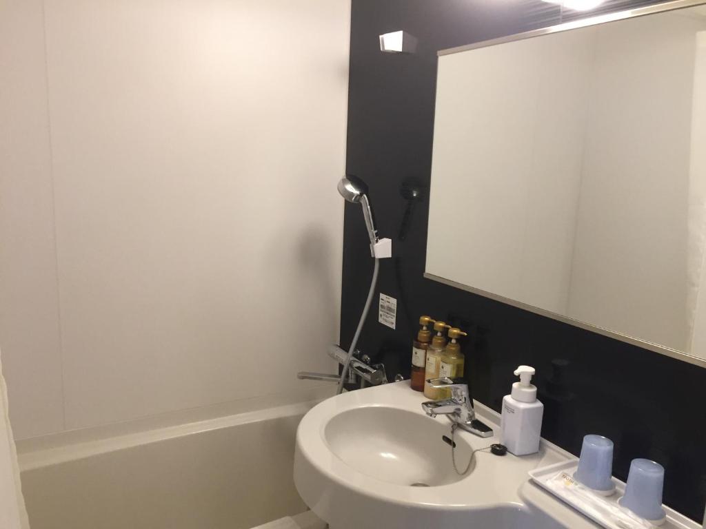 a bathroom with a white sink and a mirror at HOTEL MYSTAYS Kamata in Tokyo