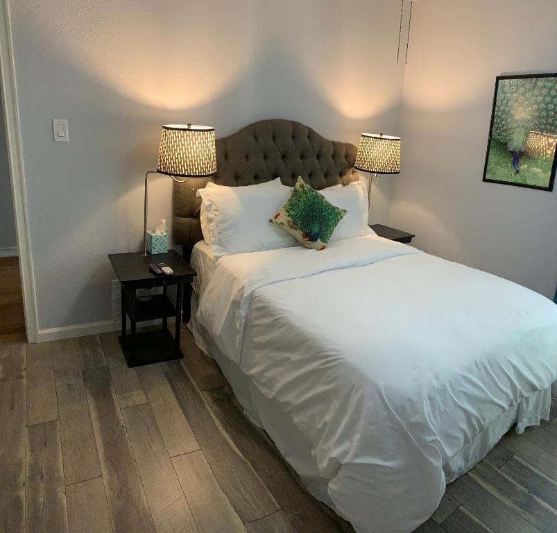 a bedroom with a large white bed with two lamps at The Peahen House in San Antonio
